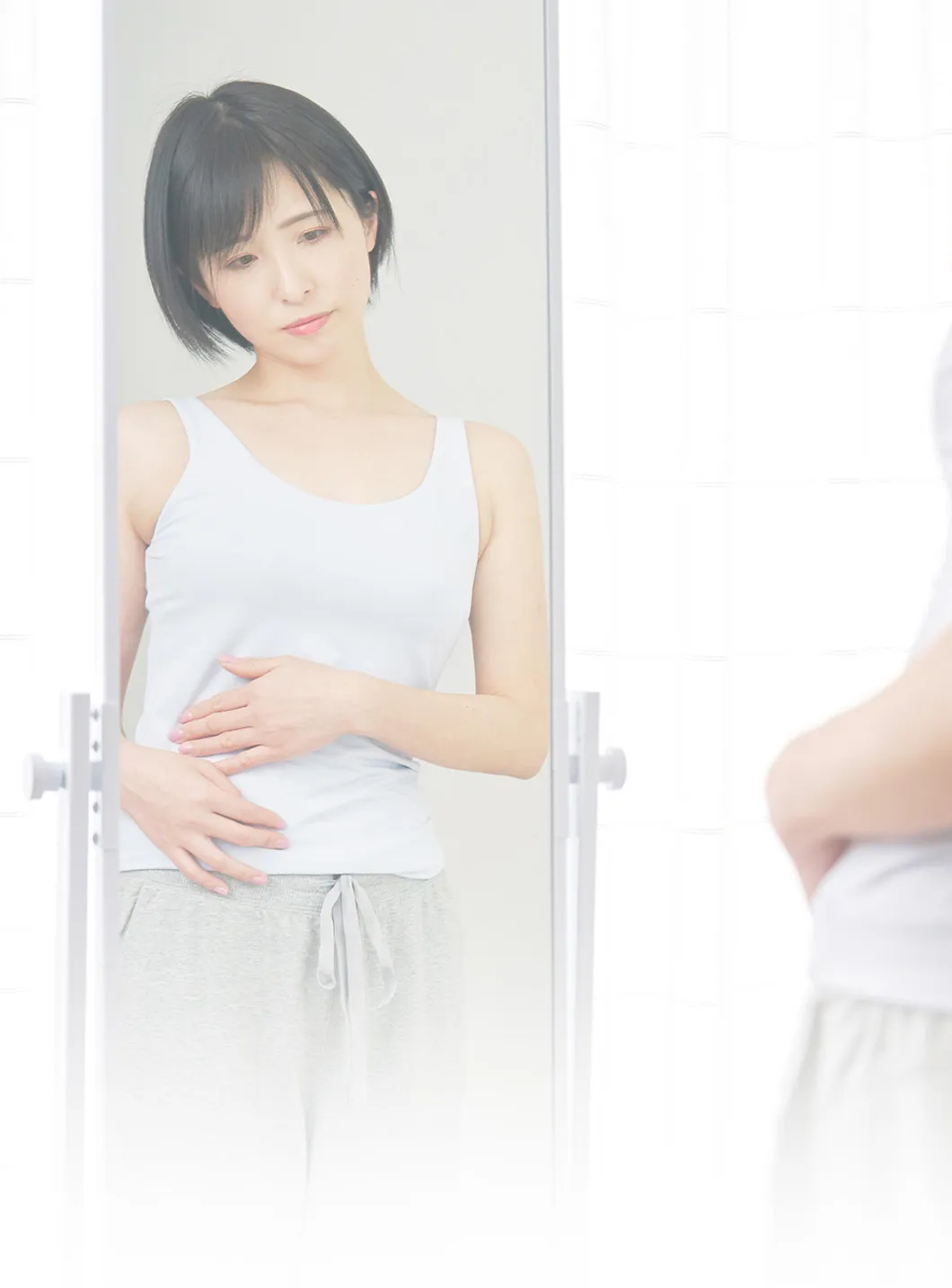 鏡の前でお腹まわりを気にする女性